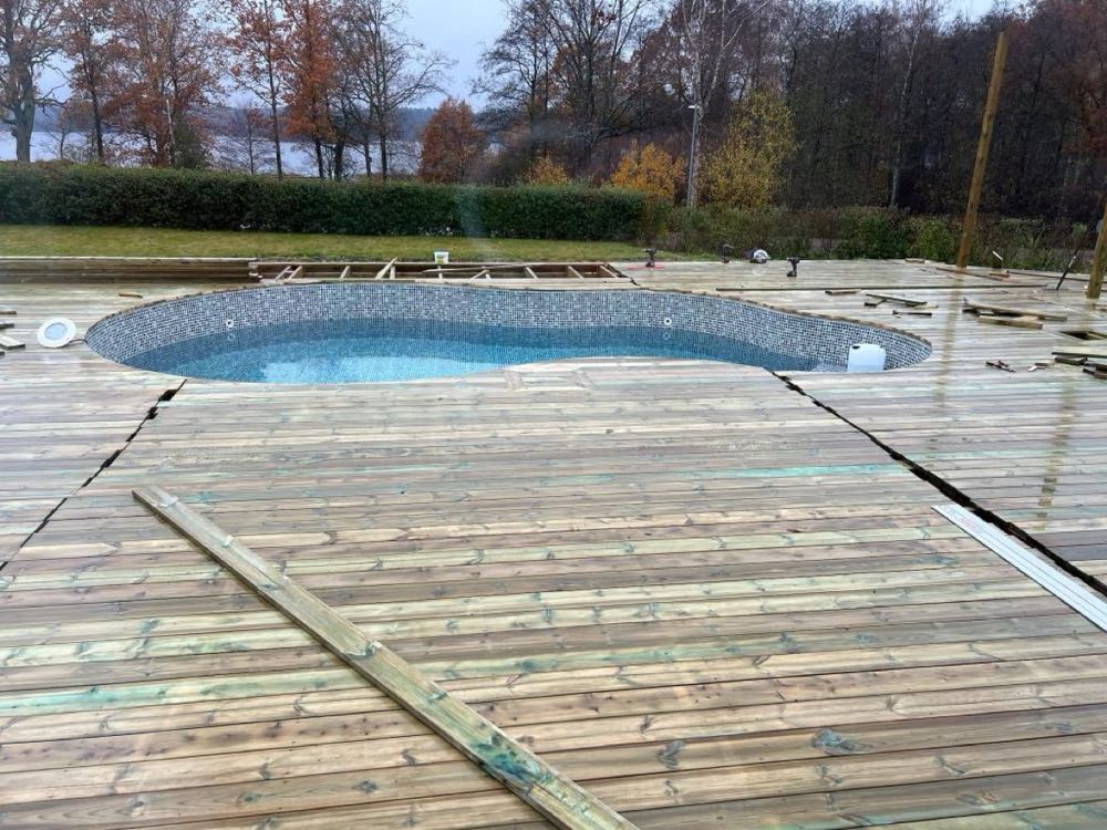 Trädäck runt pool under uppbyggnad